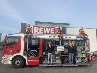 Bild vergr&ouml;&szlig;ern: Oben auf dem Fahrzeug von links nach rechts: 
Bo Anderson, stellv.Jugendwart, Sebastian Levgr&uuml;n, Ortswehrf&uuml;hrer, David Siegmund, Leiter der Kinderfeuerwehr 
Unten vor dem Fahrzeug von links nach rechts: 
Ayhan Deniz, REWE-Marktleiter , Florian Lips, Marktmitarbeiter